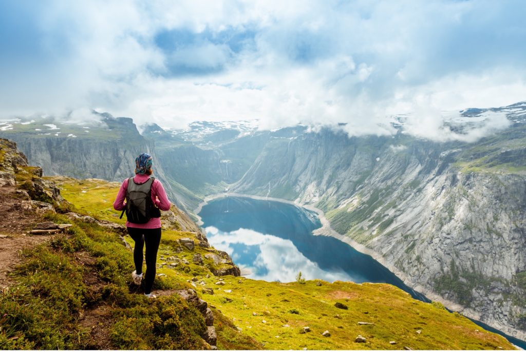 A hiker on a mountain path above a bright lake