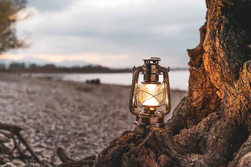 A lantern glowing at dusk beside the water
