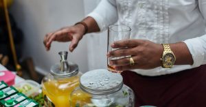 A bartender mixes drinks with fresh ingredients and juice indoors, showcasing beverage preparation.