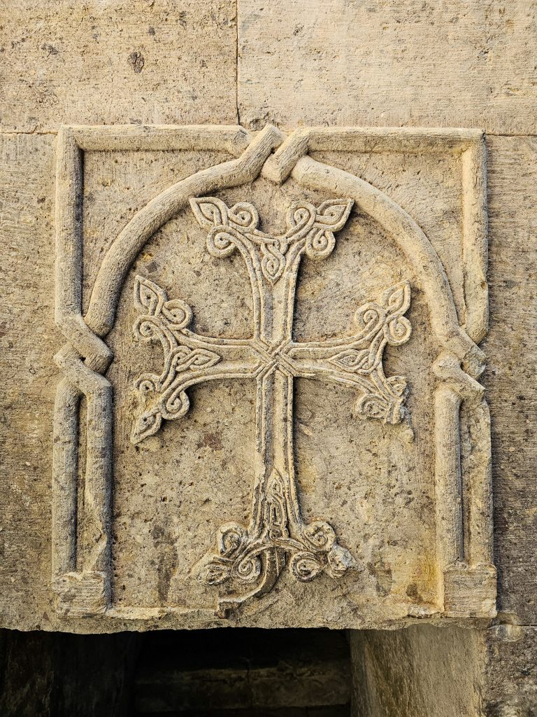 Detailed stone carving of a cross on ancient architecture with intricate patterns.