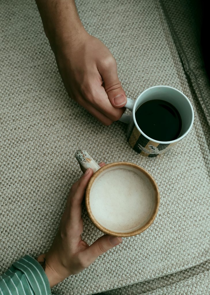 Two people enjoying drinks from mugs on a textured surface, with cozy and warm ambiance.