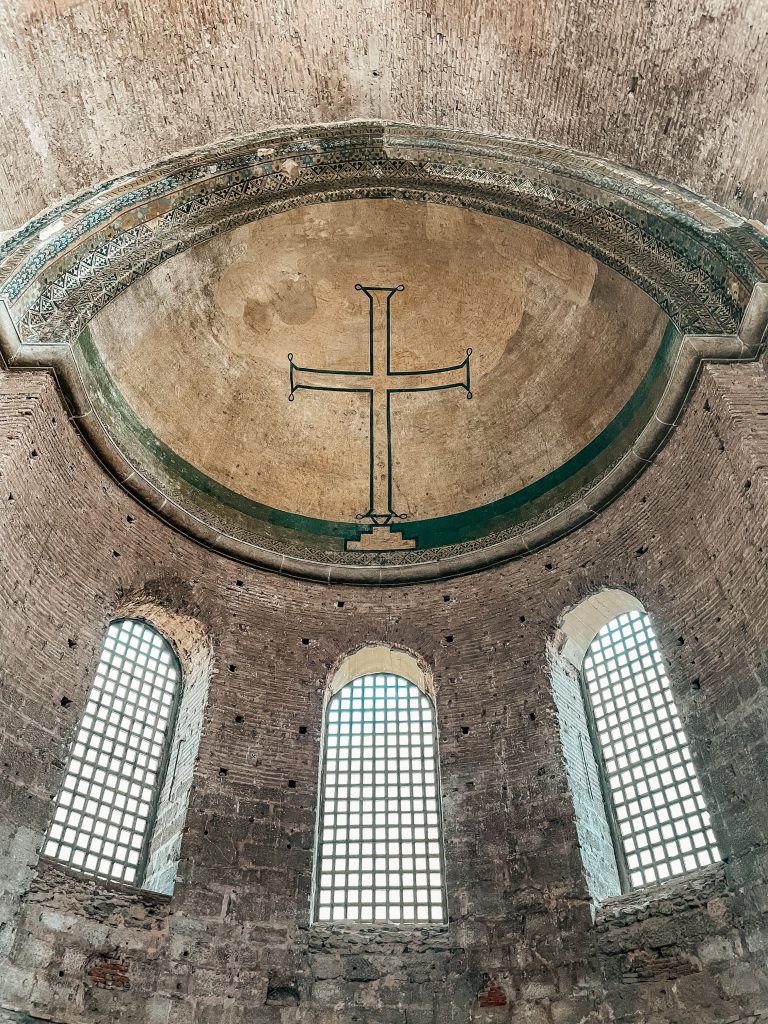 Light through the windows of an ancient church, a cross above the apse
